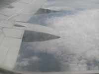 Vaizdas pro langą lėktuve matoma dalis sparno ir debesys